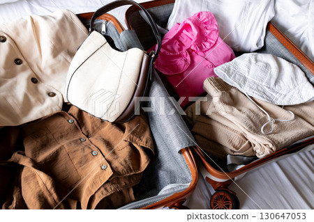 Organized travel essentials with stylish outfits and accessories in suitcase 130647053