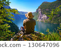 Hiker Overlooking Geiranger Fjord and Seven Sisters Waterfall in Norway 130647096