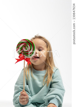Portrait of funny little blonde girl with sweets lollipop in her hand. High quality photo 130647634