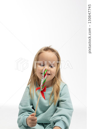Portrait of funny little blonde girl with sweets lollipop in her hand. High quality photo 130647745