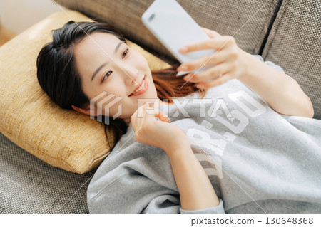 躺在沙發上使用智能手機的女人 130648368