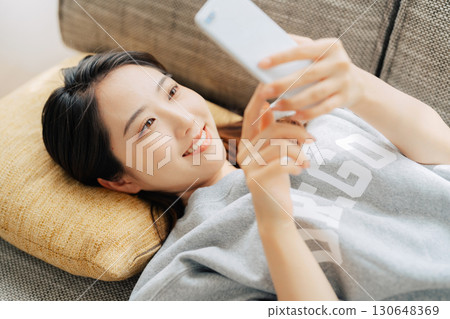 躺在沙發上使用智能手機的女人 130648369