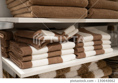 Brown and white towels neatly stacked on shelves in a modern bathroom Brown and white towels neatly stacked on shelves in a modern bathroom 130648662