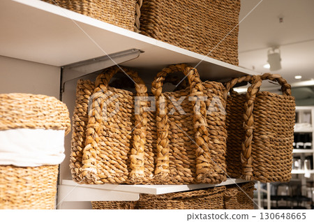 Woven straw baskets on display shelves in a retail store 130648665