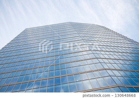 Modern glass skyscraper against blue sky with reflective windows 130648668