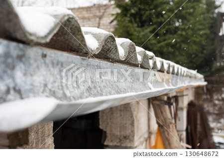 Snow-covered corrugated roof of rural building in winter Snow-covered corrugated roof of rural building in winter 130648672