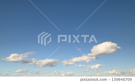 A beautiful scene features a serene sky adorned with fluffy clouds, showcasing natural beauty 130648709