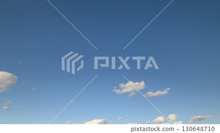 The Sky is a Clear, Bright Blue, Decorated with Fluffy, White Clouds Floating Gracefully 130648710