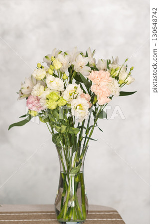 Elegant bouquet of mixed flowers in clear vase on striped tablecloth Elegant bouquet of mixed flowers in clear vase on striped tablecloth 130648742