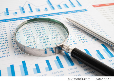 Magnifying glass on spreadsheet and graph paper. Financial data economy, Business. 130648832