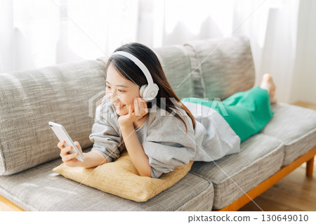 A woman listening to music and looking at her smartphone A woman listening to music and looking at her smartphone 130649010