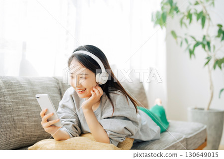 一位女士一邊聽音樂一邊看智慧型手機 130649015