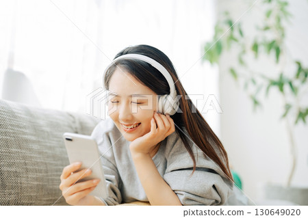 A woman listening to music and looking at her smartphone 130649020