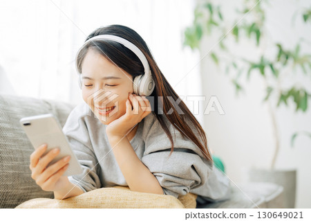 A woman listening to music and looking at her smartphone A woman listening to music and looking at her smartphone 130649021