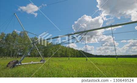 The Advanced Irrigation System in a Beautiful Lush Green Field Beneath a Bright Blue Sky 130649524