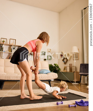 Mother and daughter having fun during a home fitness activity 130649967