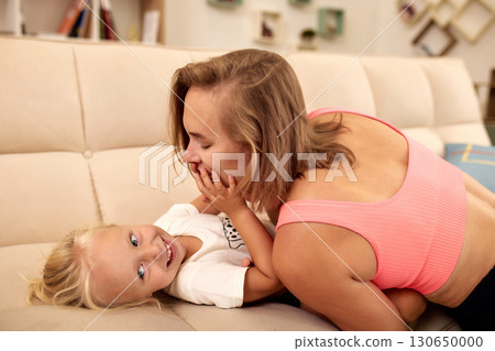 Mother and child sharing playful moments together on the living room couch Mother and child sharing playful moments together on the living room couch 130650000