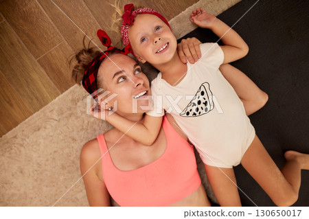 Mother and daughter bonding indoors while relaxing on a carpeted floor 130650017