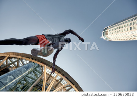 Dynamic low-angle shot of an athlete running amidst an urban skyline 130650038
