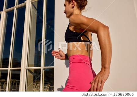 Young woman running outdoors in a pink and black fitness outfit Young woman running outdoors in a pink and black fitness outfit 130650066