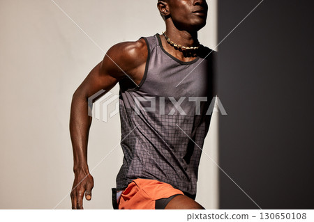 Athletic man running with determination and focus under bright natural light 130650108