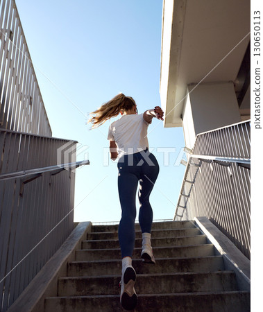 Young woman running up stairs outdoors during daytime Young woman running up stairs outdoors during daytime 130650113