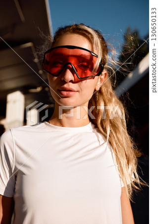 Young woman wearing stylish red-tinted goggles outdoors in bright sunlight Young woman wearing stylish red-tinted goggles outdoors in bright sunlight 130650133