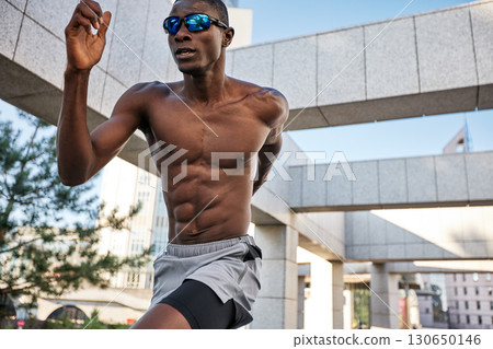 Athletic man running outdoors wearing sunglasses in modern urban environment Athletic man running outdoors wearing sunglasses in modern urban environment 130650146