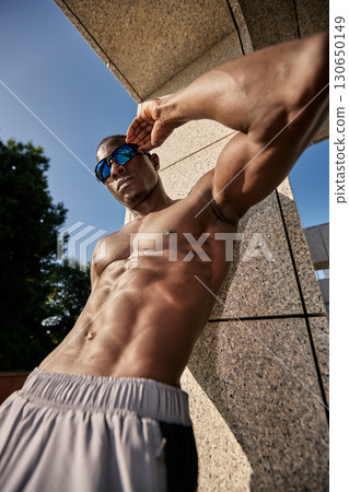 Muscular man posing outdoors in athletic wear under natural sunlight 130650149