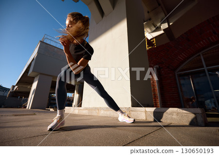Woman in sportswear performing dynamic workout in sunny urban setting Woman in sportswear performing dynamic workout in sunny urban setting 130650193