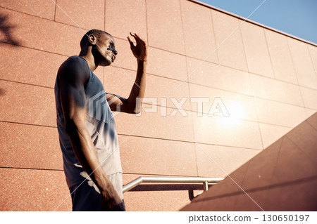 Athletic individual shielding eyes from sun in urban environment Athletic individual shielding eyes from sun in urban environment 130650197