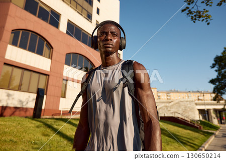Athletic man with headphones in urban park on a sunny day Athletic man with headphones in urban park on a sunny day 130650214