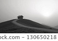 A hut on a hill lit by the setting sun 130650218