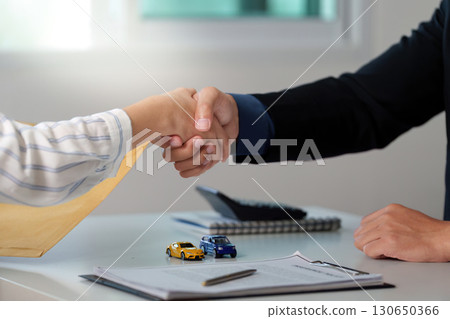 Car Dealership. A handshake between a client and a salesperson sealing a vehicle deal. 130650366