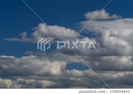 A Stunningly Beautiful Sky Displaying Fluffy Clouds Set Against a Deep Blue Background 130650441