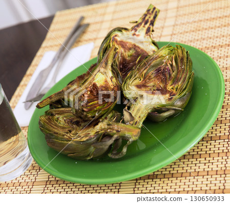 cooked fried halves artichokes on green plate 130650933