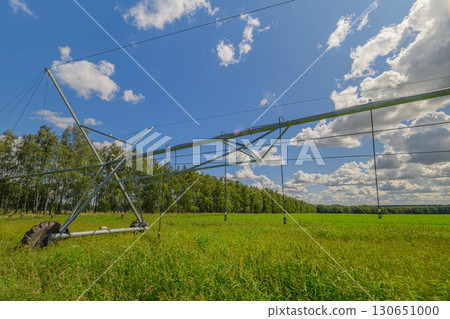 A Modern Irrigation System Operating Effectively in a Lush Green Field Beneath a Beautiful Blue Sky 130651000