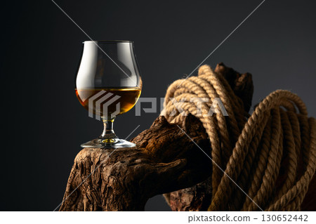 Brandy snifter and rope on a old wooden snag. Brandy snifter and rope on a old wooden snag. 130652442