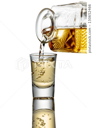 Gold liquor pouring into a glass on a white background. Gold liquor pouring into a glass on a white background. 130652466