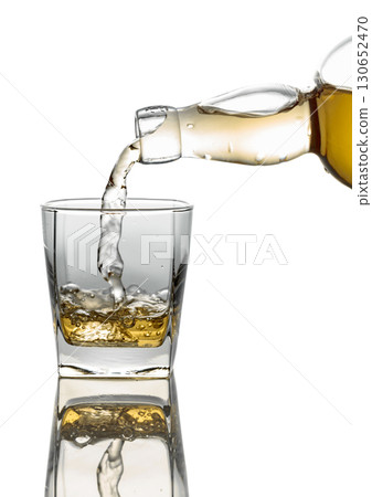 Pouring whiskey from a bottle into a glass on a white background. 130652470