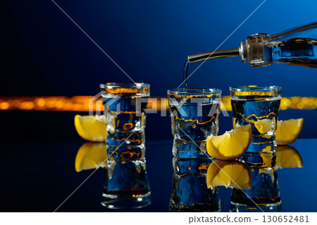 Vodka and lemon slices on a dark blue background. Vodka and lemon slices on a dark blue background. 130652481