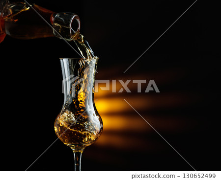 Rum being poured from a bottle into a glass. Rum being poured from a bottle into a glass. 130652499