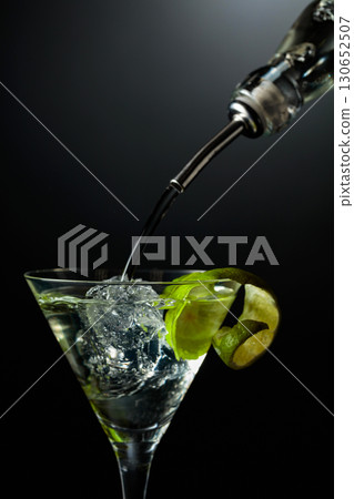 Vodka or gin is poured into a glass with ice. Vodka or gin is poured into a glass with ice. 130652507