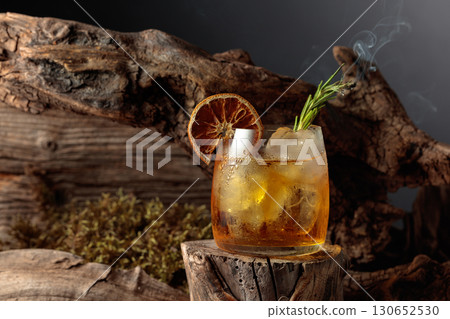 An old-fashioned cocktail over ice on an old wooden stump. An old-fashioned cocktail over ice on an old wooden stump. 130652530