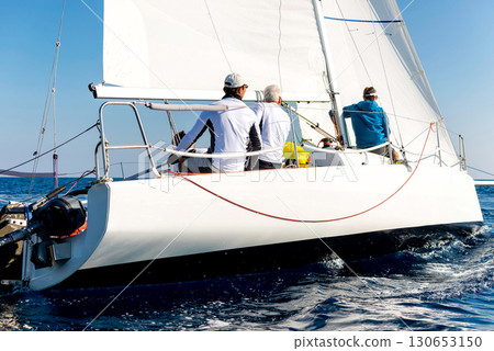 Sailing team maneuvering a yacht at sea in a regatta race Sailing team maneuvering a yacht at sea in a regatta race 130653150