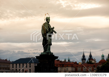 Bronze statue of St. John of Nepomuk on Charles Bridge with Prague's skyline in the backdrop, Czech Republic 130653179