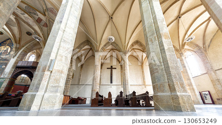 Inside a Emmaus Monastery featuring towering stone columns and an arched ceiling 130653249