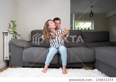 Mother and son share a joyful moment on a couch 130653254