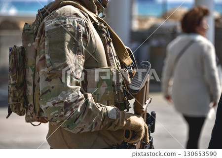 Soldier is holding a rifle and patrolling a city street 130653590