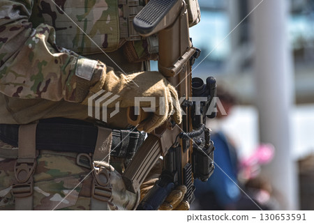 Soldier holding modern assault rifle with scope and tactical gear 130653591